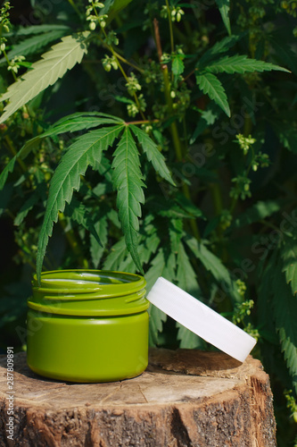 Jar of hemp lotion on blurry background with copy space. Cannabis cream with leaf marijuana - topical cannabis concept. Cream of biological and ecological plants hemp vegetable pharmaceutical oil CBD