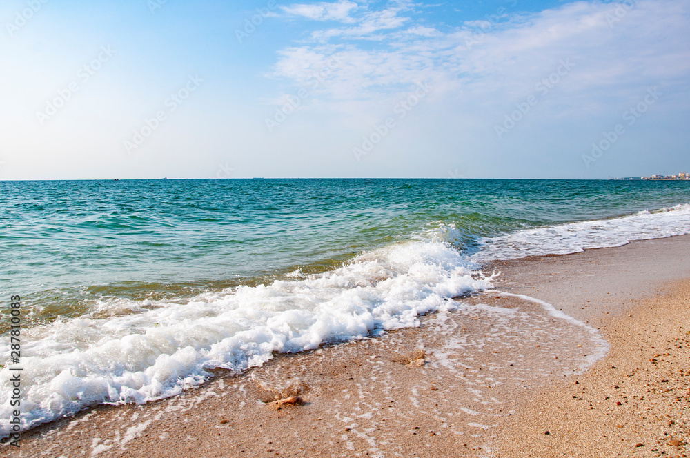 .Sea shore waves sand stones beautiful clouds on blue sky. .Sea shore waves sand stones beautiful clouds on blue sky.