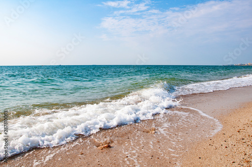 .Sea shore waves sand stones beautiful clouds on blue sky.