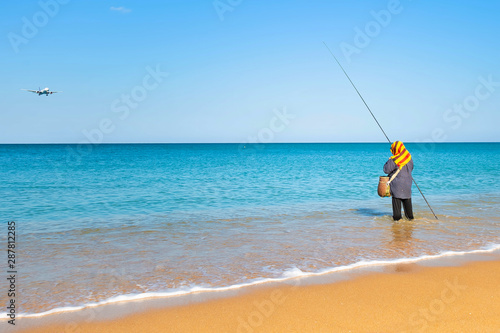 Woman fishing standing in the water near the shore. The sky is dropping the plane. Sunny clear morning on a tropical beach.