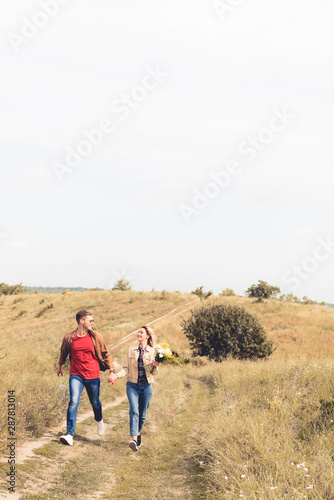 attractive woman with bouquet and handsome man smiling and holding hands