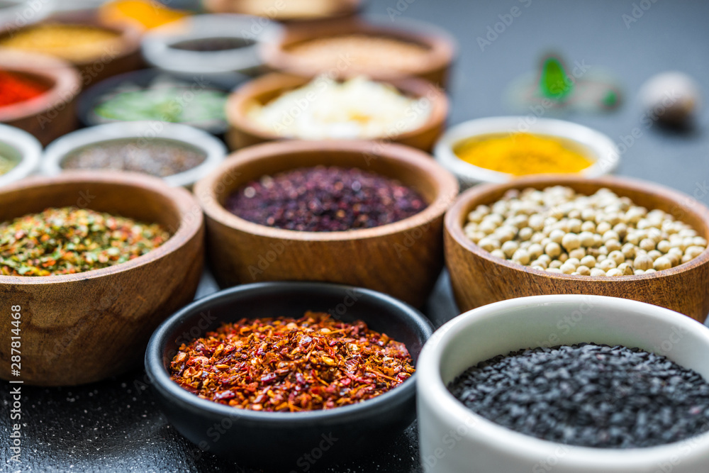 Variety of colorful spices, herbs, and seeds on black stone background Variety of colorful spices, herbs, and seeds on black stone background