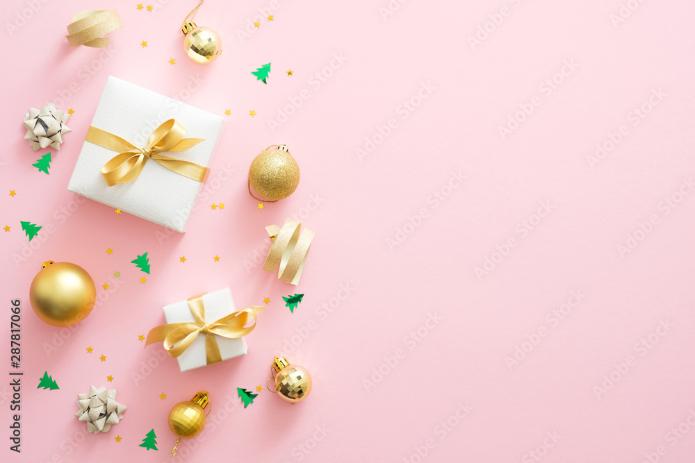 Christmas composition. Christmas golden decorations, gift boxes, baubles, confetti on pastel pink background with copy space. Flat lay, top view