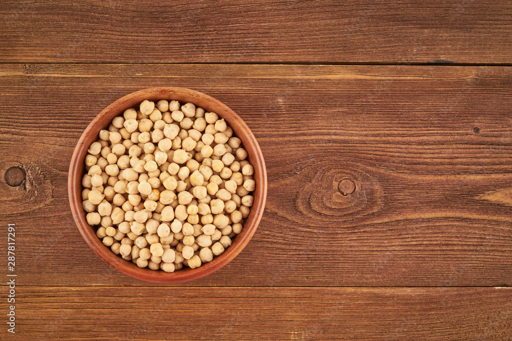 Dried chickpea in wooden bowl on brown background, top view, copy space Dried chickpea in wooden bowl on brown background, top view, copy space