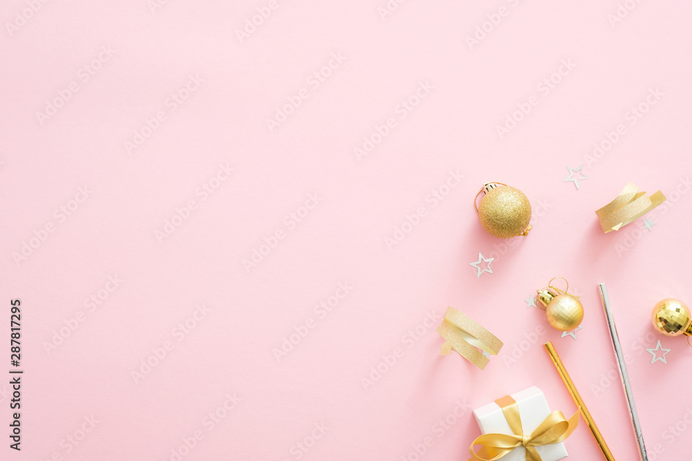 Christmas golden decorations on pastel pink background with copy space. Minimal flat lay style composition, top view. Christmas party invitation card mockup. Xmas fashion glamour concept.