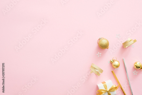 Christmas golden decorations on pastel pink background with copy space. Minimal flat lay style composition, top view. Christmas party invitation card mockup. Xmas fashion glamour concept.