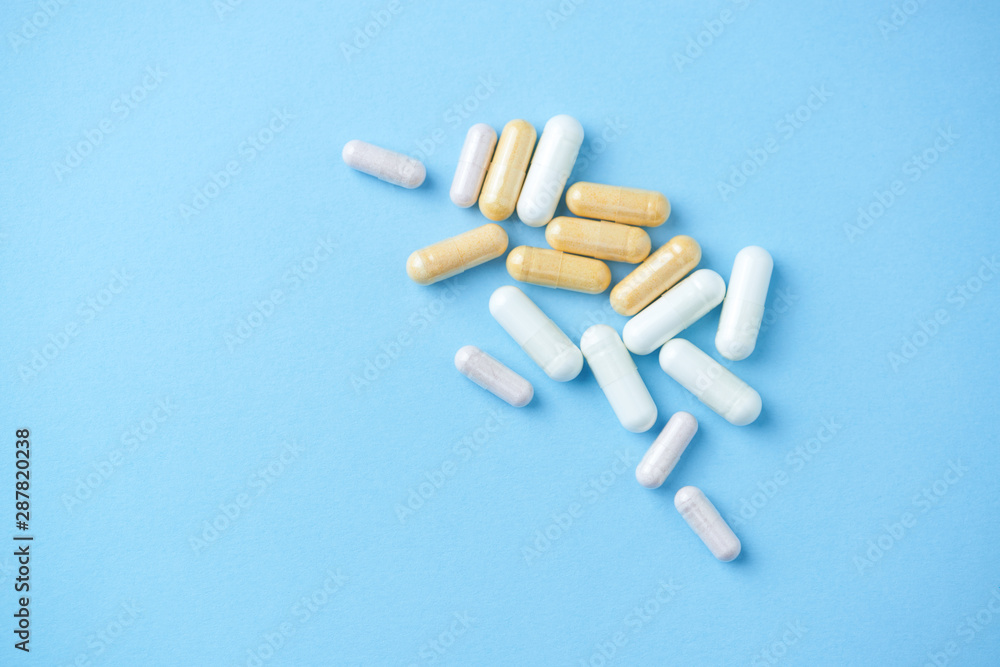 Vitamins and supplements on bright paper background. Concept for a healthy dietary supplementation. Close up. Copy space. Vitamins and supplements on bright paper background. Concept for a healthy dietary supplementation. Close up. Copy space.