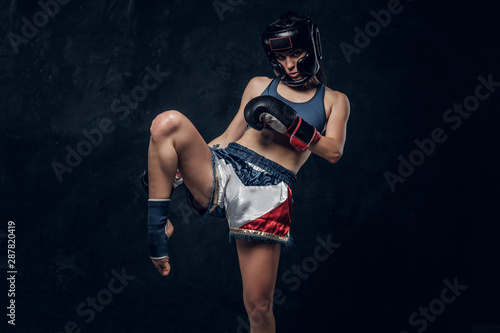 Fototapeta Naklejka Na Ścianę i Meble -  Pretty strong woman is demonstrating her kick boxer pose while posing for photographer.