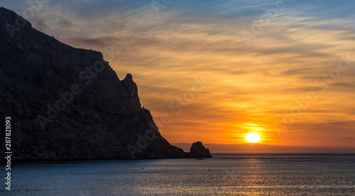 Fantastic sunrise at Cabo Antonio near the Spanish city Javea. Exciting clouds in orange shades decorate the sky over the Mediterranean Sea. photo