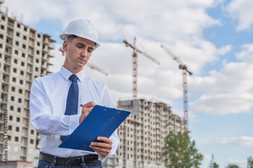civil engineer in a white helmet makes pencil marks in the documentation. civil engineer in a white helmet makes pencil marks in the documentation.