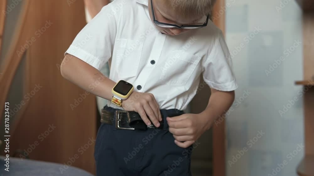 The guy is going to school, puts a belt on his pants The guy is going to school, puts a belt on his pants