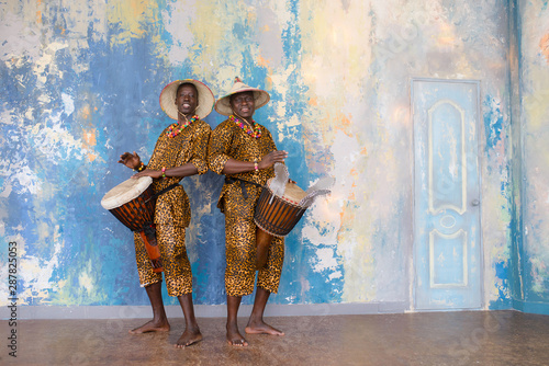 A group of people in traditional african costumes playing jembe drums
