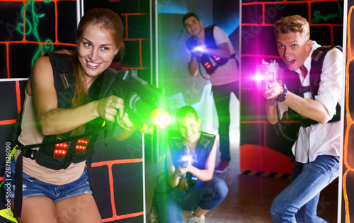 Young excited people in vests and with laser pistols playing las