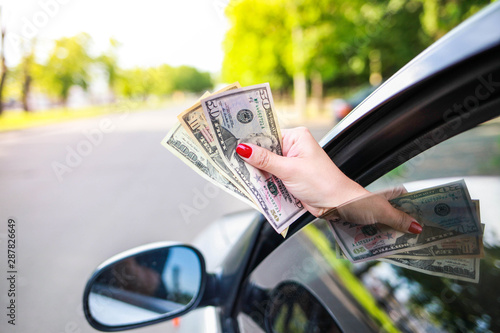 Foto young pretty girl driving holds money from a car window