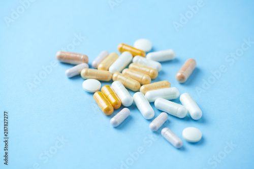 Vitamins and supplements on bright paper background. Concept for a healthy dietary supplementation. Close up. Copy space. 