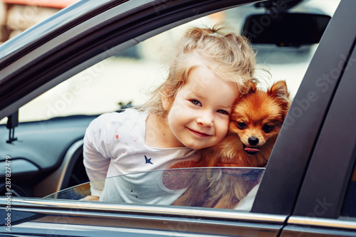 Little girl and little dog in the rent car © matilda553