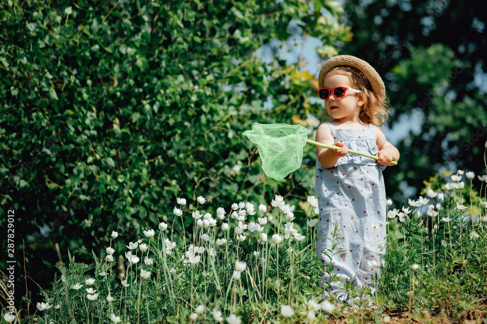 Adorable little girl catching butterflies and bugs with her scoop-net.