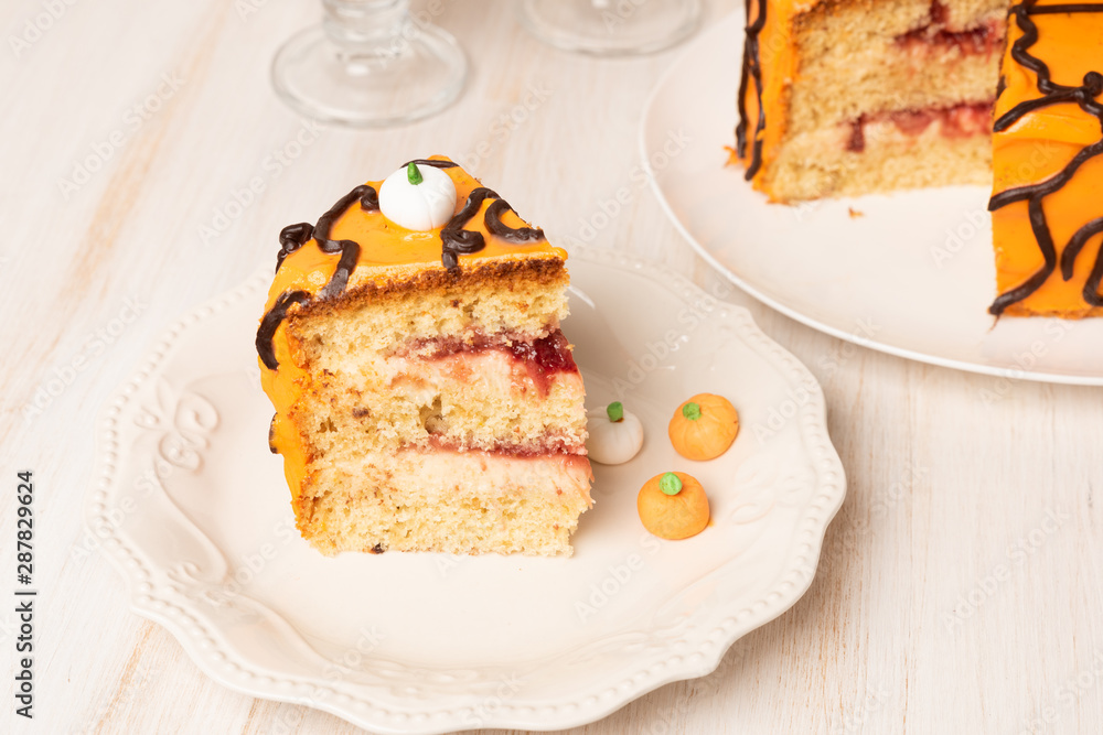 Pumpkin or carrot cake with cream cheese frosting decorated with candy, dessert for Halloween and Thanksgiving on wooden table Pumpkin or carrot cake with cream cheese frosting decorated with candy, dessert for Halloween and Thanksgiving on wooden table