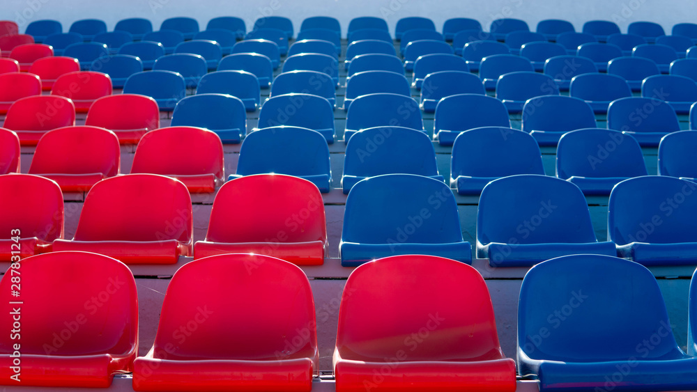 Fototapeta premium Bleachers in a sports stadium. Red and blue seats in a large street stadium.