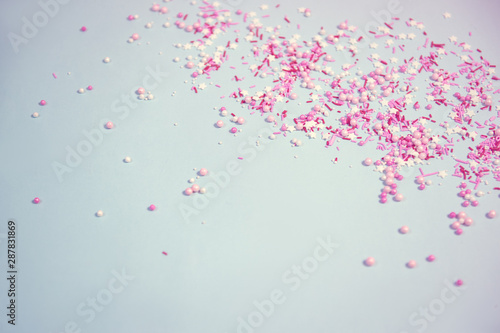 Colorful sprinkles on blue background, top view with copy space
