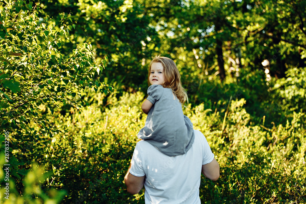 Dad carries his daughter on his shoulders across the field at sunset. Dad carries his daughter on his shoulders across the field at sunset.
