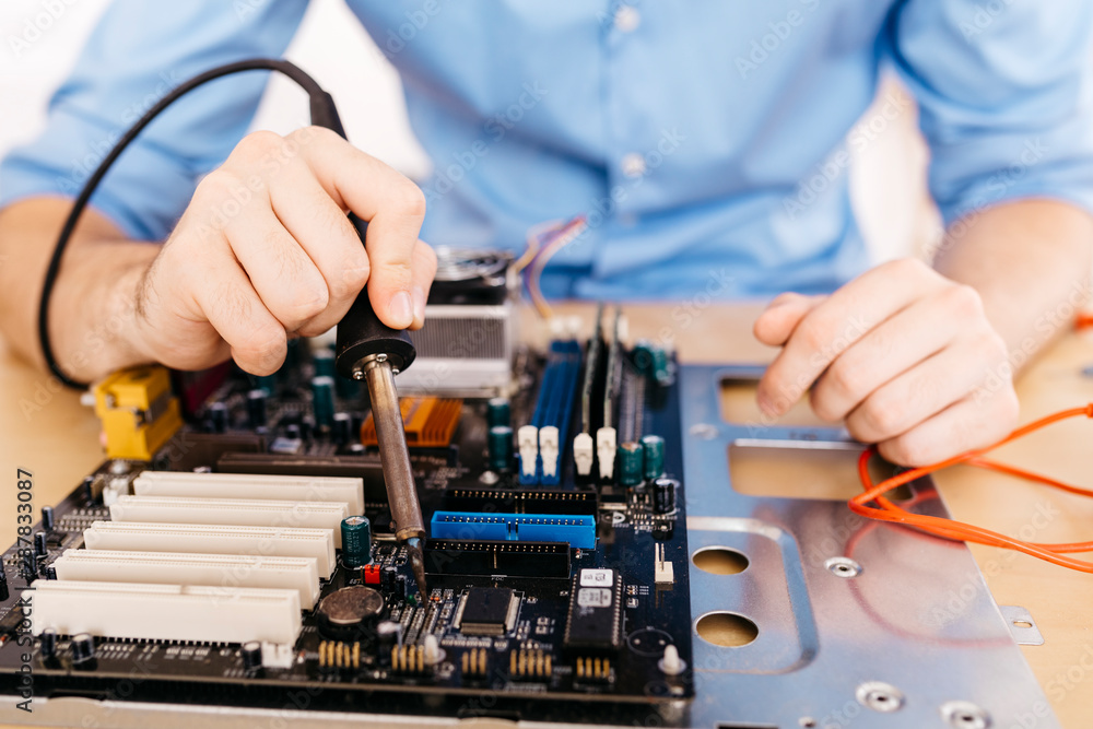 Close-up of technician repairing a desktop computer, soldering a component with tin Close-up of technician repairing a desktop computer, soldering a component with tin