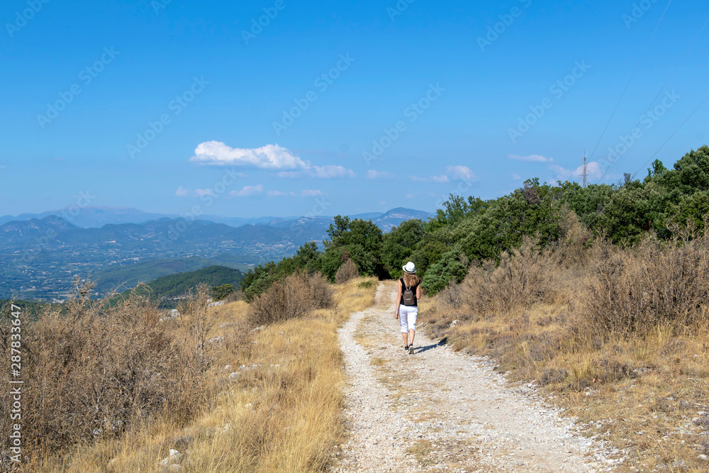 Independent solo traveler woman on the road at Dentelles de Montmirail chain of mountains in Provence in Vaucluse, France