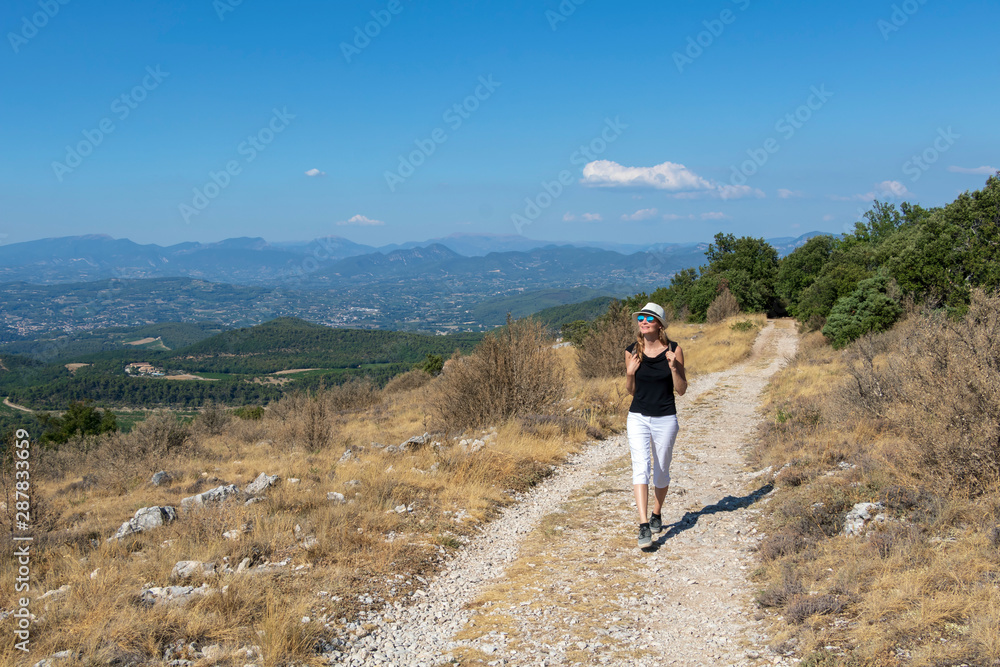 Independent solo traveler woman on the road at Dentelles de Montmirail chain of mountains in Provence in Vaucluse, France