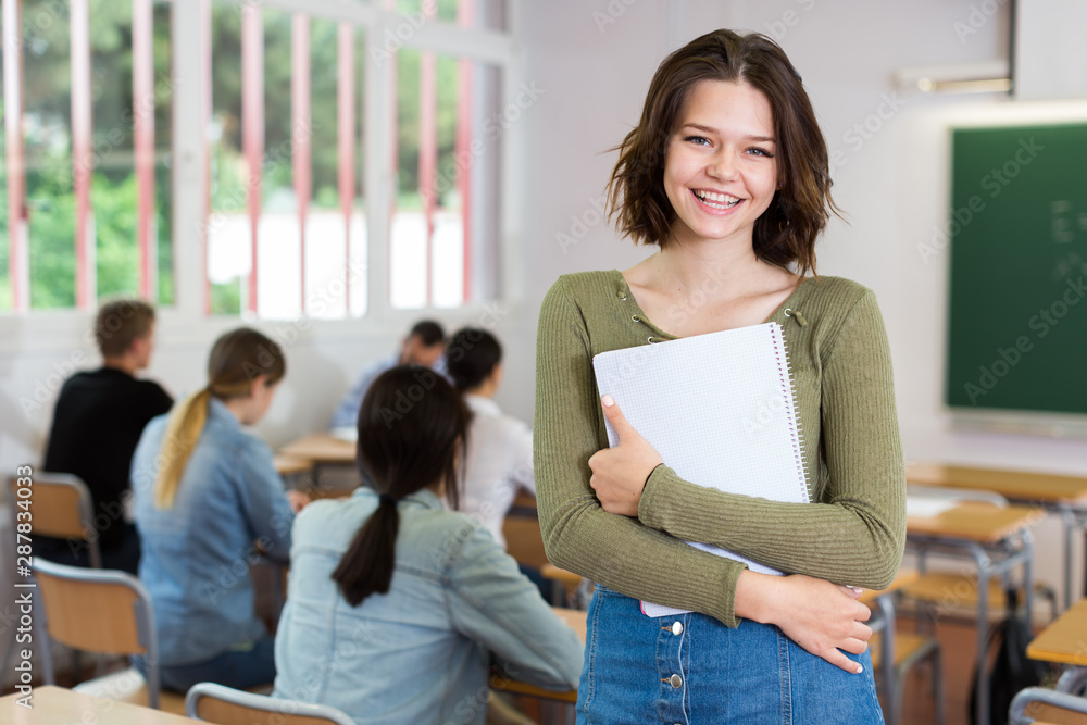 Portrait of girl who is standing satisfied after lecture in the classroom - obrazy, fototapety, plakaty 