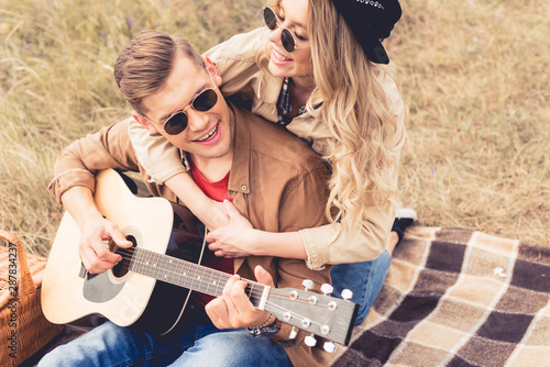 handsome man playing acoustic guitar and attractive woman hugging him