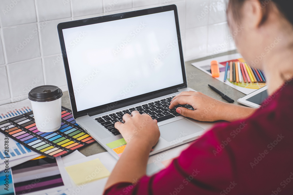 Fototapeta premium Young creative graphic designer working on project architectural drawing and color swatches, selection coloring on graphic chart with work tools and equipment