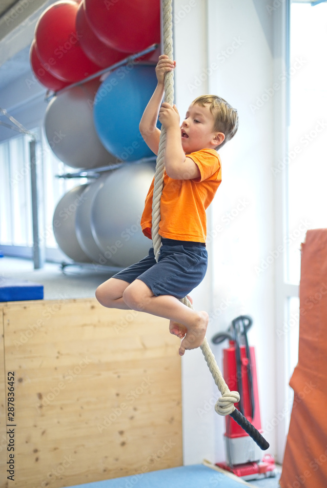 Little boy gymnast climbs a rope Little boy gymnast climbs a rope