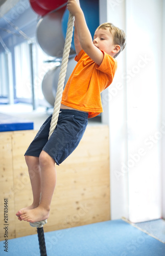 Little boy gymnast climbs a rope