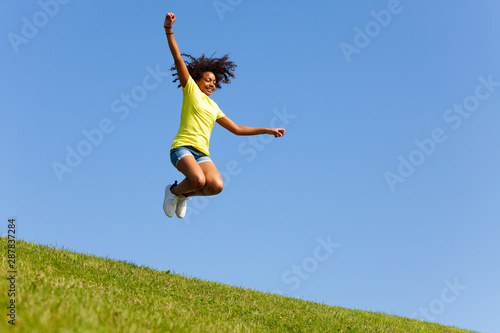 Girl with flying hair jump high on the lawn