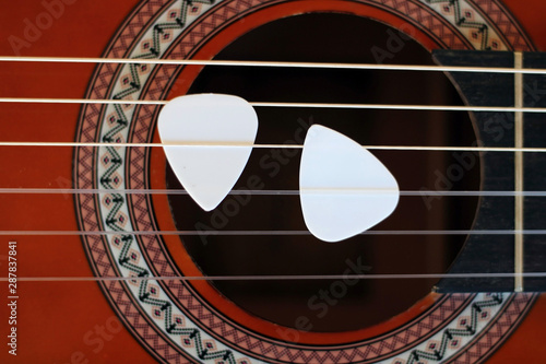 Guitar picks on the fingerboard of a brown guitar. photo