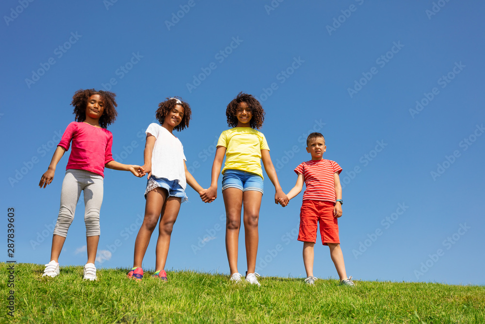 Group of children stand hold hand over clean sky Group of children stand hold hand over clean sky