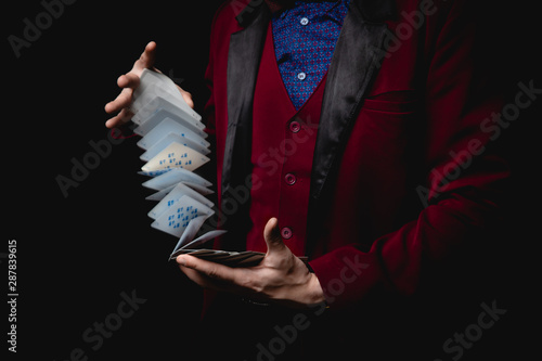 Photographie Magician shows trick with playing cards, dark background