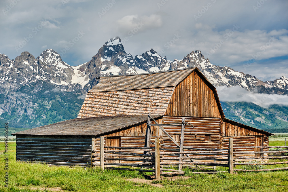 Old mormon barn in Grand Teton Mountains with low clouds. Grand Teton National Park, Wyoming, USA. Old mormon barn in Grand Teton Mountains with low clouds. Grand Teton National Park, Wyoming, USA.