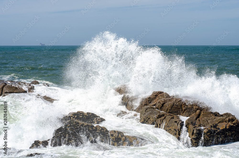 Wave with foam breaking of rock in ocean or sea