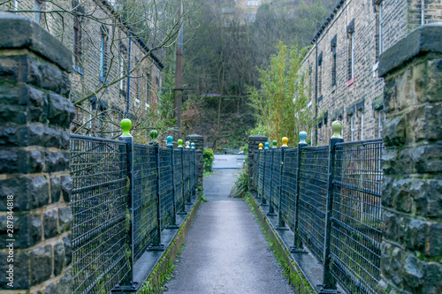 small footpath through terraced houses with railings in a mill town.