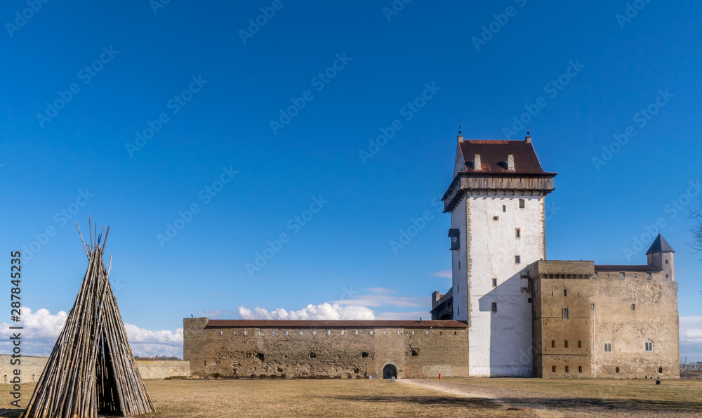 Narva or Hermann castle on a sunny day with a wooden tepee made from wood. 