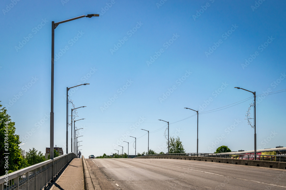 A row of street lights spanning an arched road on a sunny day