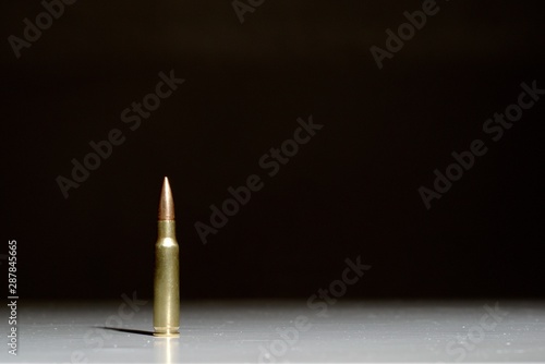 Large bullet (7.62 x 51 mm NATO) standing on a white surface with a black background