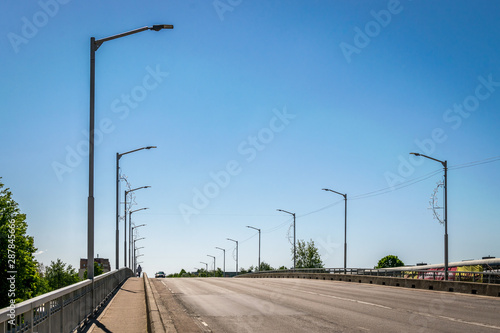 A row of street lights spanning an arched road on a sunny day. 