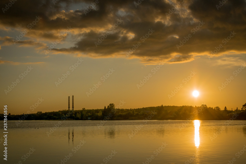 a sunset over the Narva reservoir with two chimneys from a power plant.  