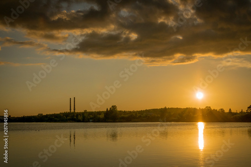 a sunset over the Narva reservoir with two chimneys from a power plant. 