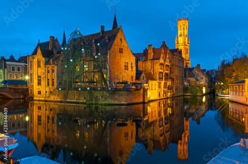 Long exposure photograph of the canals in Bruges by the Rozenhoedkaai during the blue hour with the illuminated belfry and medieval architecture, West Flanders, Belgium.