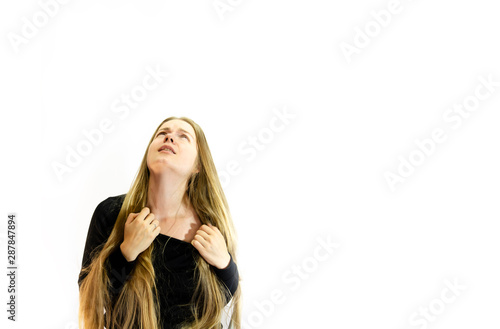 A girl with long blonde hair is in pain, dressed in a black sweatshirt, hands tearing his neck and looking up at the light, on a white background