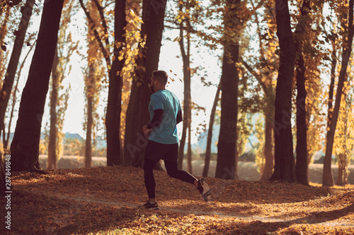 Close-up of man jogging on sunny autumn morning outdoors.