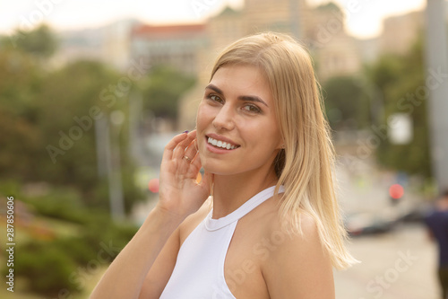 Outdoors lifestyle fashion portrait of happy stunning blonde girl. Beautiful smile. Walking to the city street. Long light hair. Joyful and cheerful woman. Happiness.